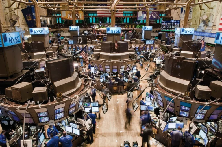 Traders at work on the bustling floor of the New York Stock Exchange (NYSE), surrounded by screens displaying financial data, representing the modern financial market