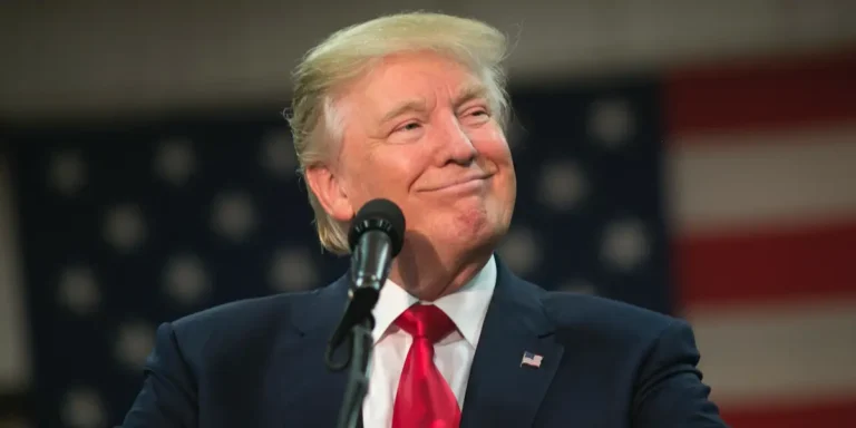 Donald Trump speaking at a podium with the American flag in the background. Discussing Trump's controversial actions 2025