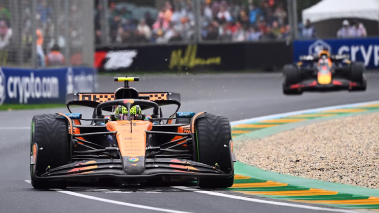 Lando Norris car speeding through the wet Albert Park Circuit during the Australian Grand Prix, with rain spraying dramatically from the tires