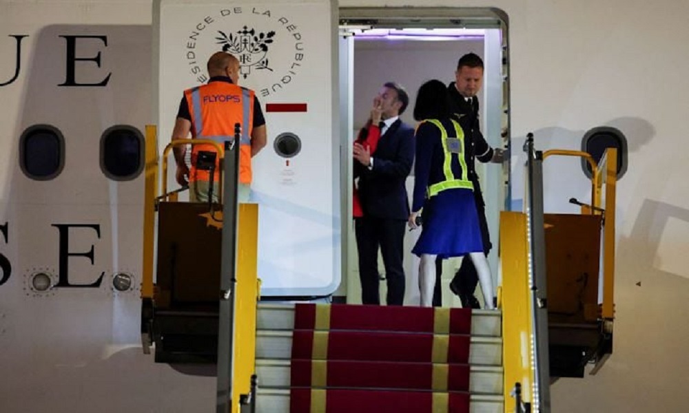 French President Emmanuel Macron reacts as Brigitte Macron playfully touches his face upon arrival in Vietnam.